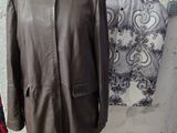 un manteau en cuir marron posé sur un mannequin devant un mur