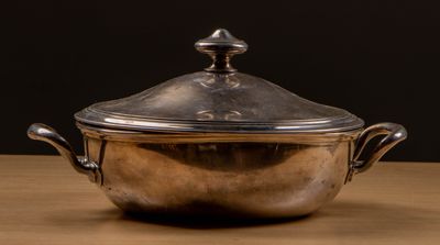 un pot en argent posé sur une table en bois, sur fond noir