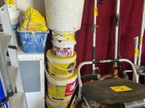 Plusieurs seaux et outils sont empilés les uns sur les autres dans un garage