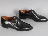 une paire de chaussures en cuir noir avec une boucle dorée