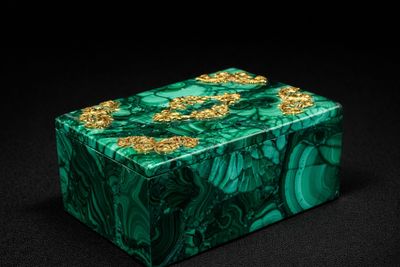 a green marble box with gold flowers on it