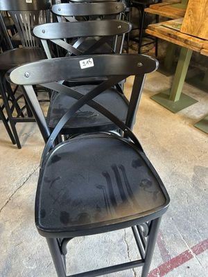 Plusieurs chaises noires sont empilées les unes sur les autres dans une pièce