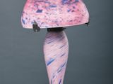 une lampe rose et bleue posée sur une table en marbre, avec un cordon noir