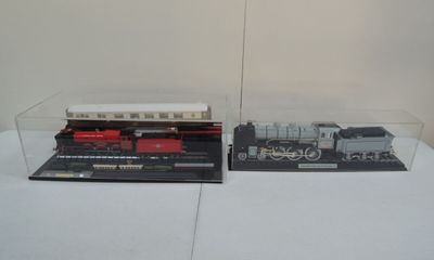 deux trains miniatures dans une vitrine posée sur une table