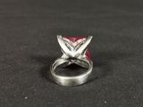 a close up of a silver ring with a red stone in it