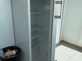 an open refrigerator in a kitchen with a trash can next to it