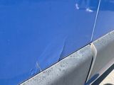a blue car that has a hole in the side of it