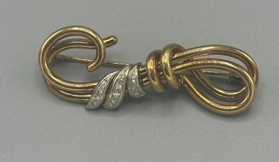 une photo en gros plan d'une broche en forme de nœud, en or et diamants