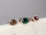 three rings with different colored stones on a marble surface