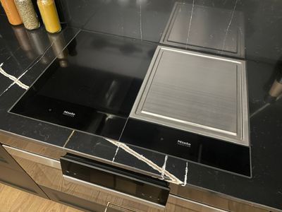une photo d'une cuisine avec un plan de travail noir et des appareils électroménagers en acier inoxydable