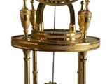 une horloge dorée posée sur un socle, sur fond blanc