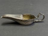an antique silver plated sauce boat with a handle on a table