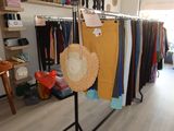 a rack of clothes and hats on display in a clothing store