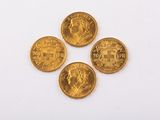 four gold sovereigns sitting on top of each other on a white surface