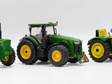 three toy tractors sitting next to each other on a white surface