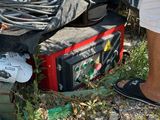 un homme debout à côté d'un tas d'appareils électroniques au bord de la route