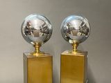 pair of chrome and brass globe lamps on pedestals on a table