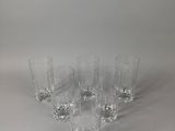 six verres transparents sont alignés sur une surface blanche