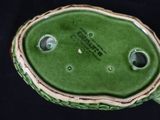 a close up of a green vase with holes in it