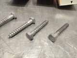 four screws on a metal table with a book in the background