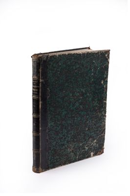 an old book with a green cover on a white surface