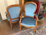 two blue chairs sitting next to each other in front of a fireplace