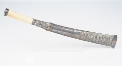 une grande corne munie d'un manche en bois, posée sur une surface blanche