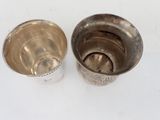 two silver cups sitting next to each other on a table