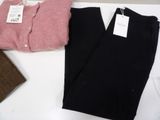 two pairs of black pants and a pink sweater on a table