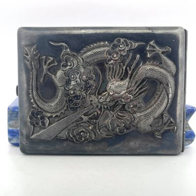 a silver belt buckle with a dragon and flowers on it