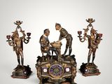 three bronze figurines of a man and a woman sitting on top of a table