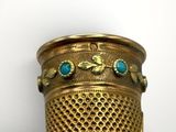 a close up of a gold vase with blue stones on it