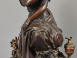 une statue de femme assise sur une table à côté d'une horloge
