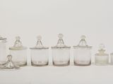 many glass jars and a bottle on a white surface
