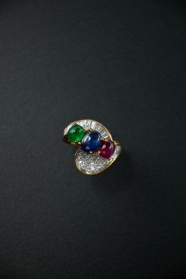 a close up of a ring with multi colored stones on a black surface