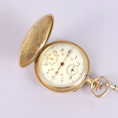 a gold pocket watch sitting on a white surface