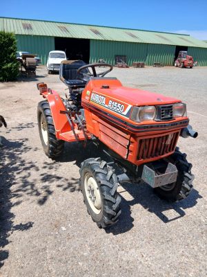 a red tractor parked in front of a green building