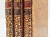 two old books sitting on top of each other on a white surface