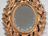 a mirror with a gold frame and a leaf decoration on it