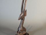 statue d'une antilope posée sur un socle en bois, sur fond gris