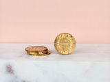 two gold coins sitting on top of a marble slab