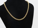 a gold chain necklace on a black mannequin