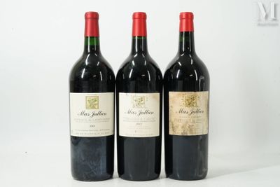 trois bouteilles de vin rouge sont alignées sur une surface blanche