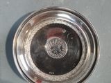 a silver plate on the floor next to a bottle of wine