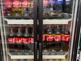 bottles of soda and soft drinks are on display in a cooler