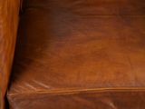 a close up of a brown leather chair on a wooden floor