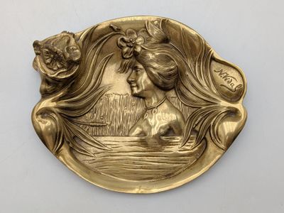 une image représentant une assiette en or sur laquelle figure une femme dans un bateau