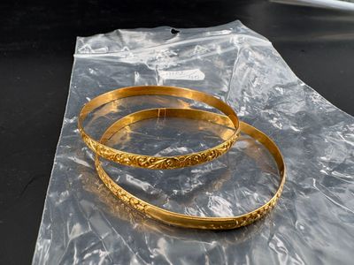 deux bracelets en or dans un sac en plastique posé sur une table