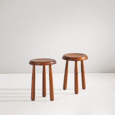 une paire de tabourets en bois posés sur une surface blanche