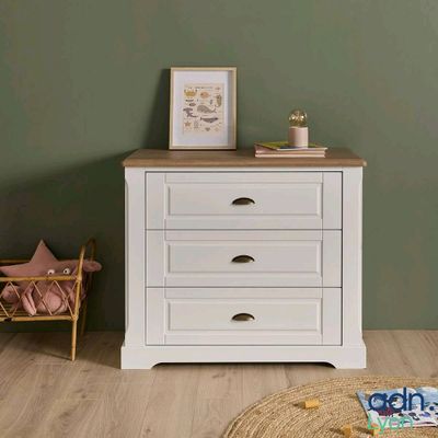 a white chest of drawers in a room with green walls